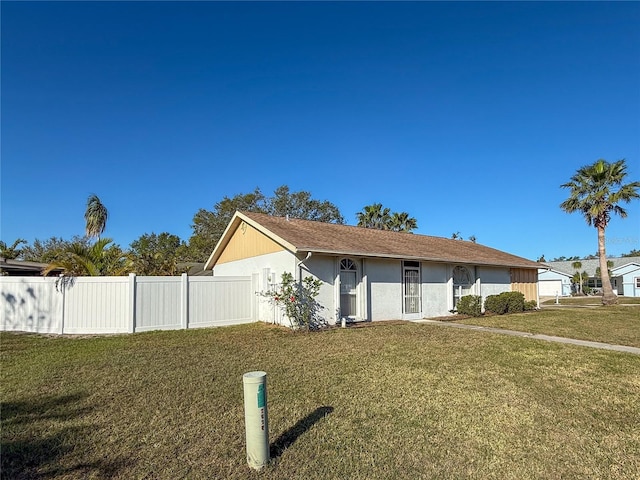 ranch-style house featuring a front lawn, fence, and stucco siding