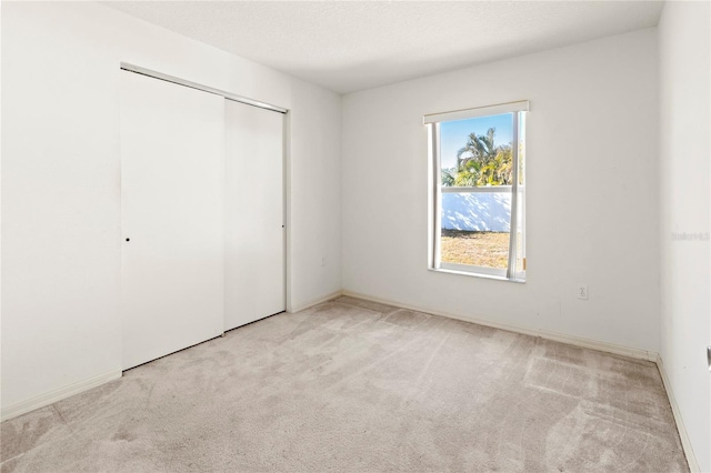 unfurnished bedroom featuring baseboards, carpet, a closet, and a textured ceiling