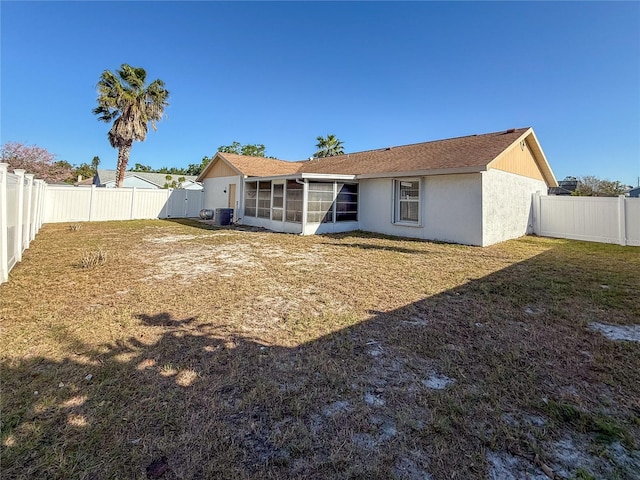 rear view of house featuring stucco siding, a yard, a fenced backyard, and a sunroom