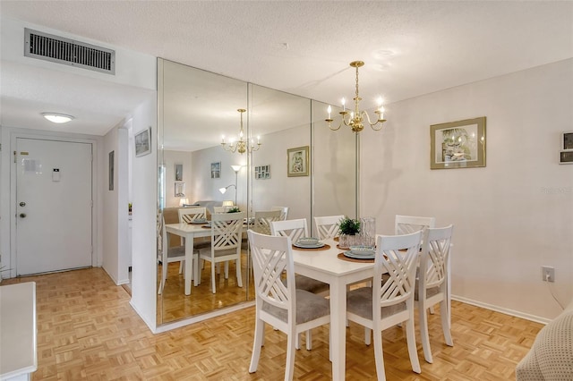 dining space with a notable chandelier, visible vents, a textured ceiling, and baseboards