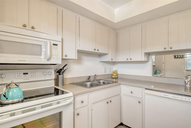 kitchen with a sink, white appliances, white cabinetry, and light countertops