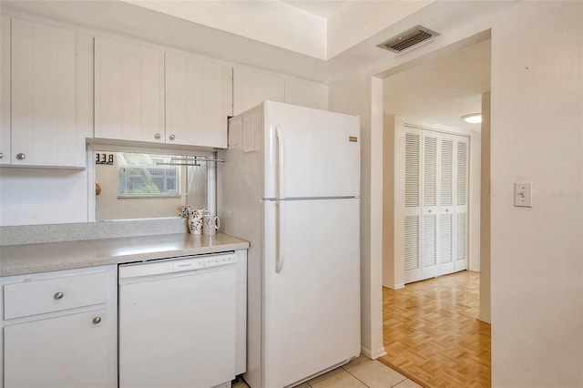 kitchen with white appliances, white cabinets, light countertops, and visible vents