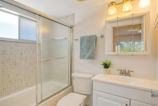 bathroom featuring vanity, toilet, plenty of natural light, and enclosed tub / shower combo