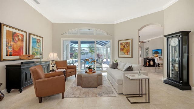 living area featuring arched walkways, light tile patterned flooring, and ornamental molding