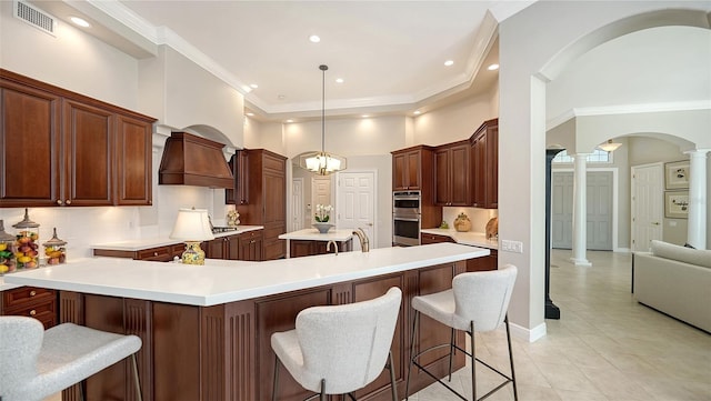 kitchen featuring tasteful backsplash, a center island, double oven, arched walkways, and ornate columns