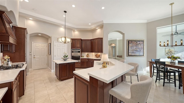 kitchen featuring arched walkways, appliances with stainless steel finishes, a kitchen island, and light countertops