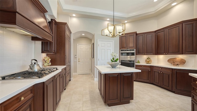 kitchen featuring custom range hood, a tray ceiling, appliances with stainless steel finishes, light countertops, and a chandelier