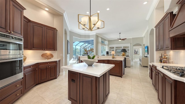 kitchen featuring a center island, open floor plan, light countertops, appliances with stainless steel finishes, and arched walkways