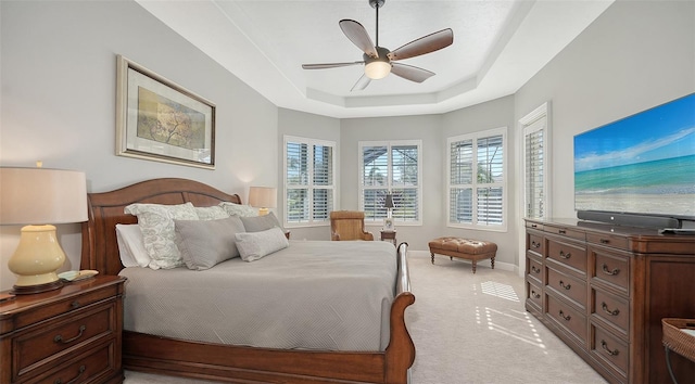 bedroom with ceiling fan, a raised ceiling, baseboards, and light carpet