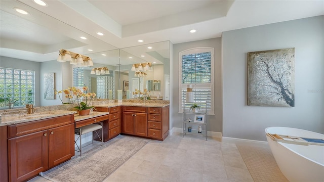 full bath with vanity, baseboards, recessed lighting, a freestanding bath, and a raised ceiling