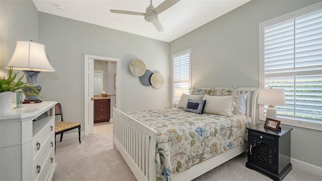 bedroom with connected bathroom, baseboards, light colored carpet, and ceiling fan