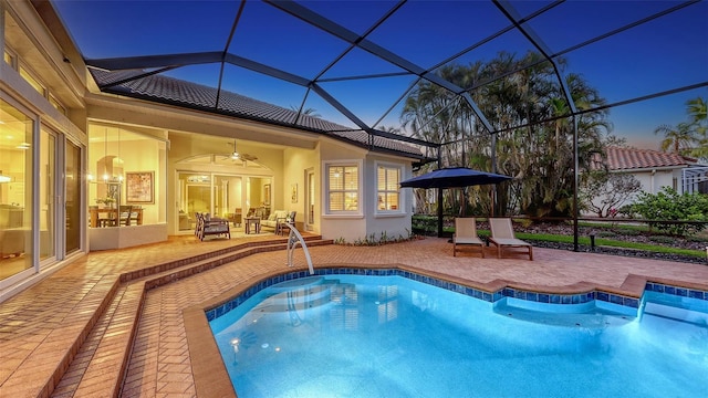 outdoor pool featuring glass enclosure, a patio, and a ceiling fan