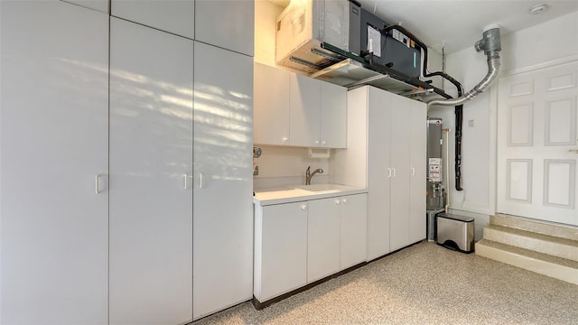 kitchen with white cabinetry, light countertops, light speckled floor, and a sink