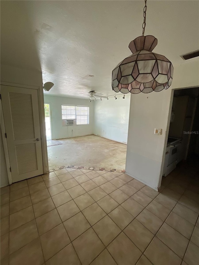 unfurnished dining area with cooling unit, visible vents, ceiling fan, a textured ceiling, and light carpet