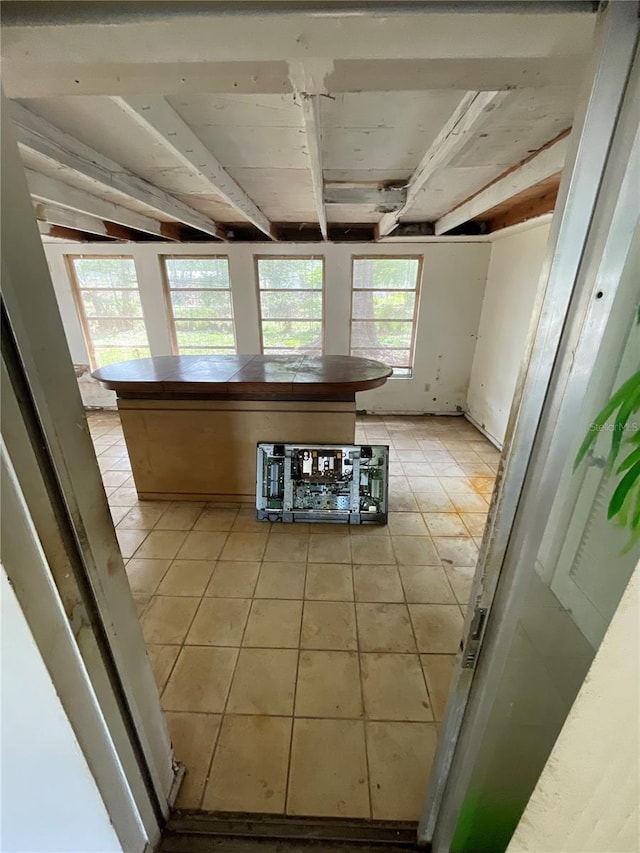 kitchen featuring light tile patterned floors, beamed ceiling, and tile countertops