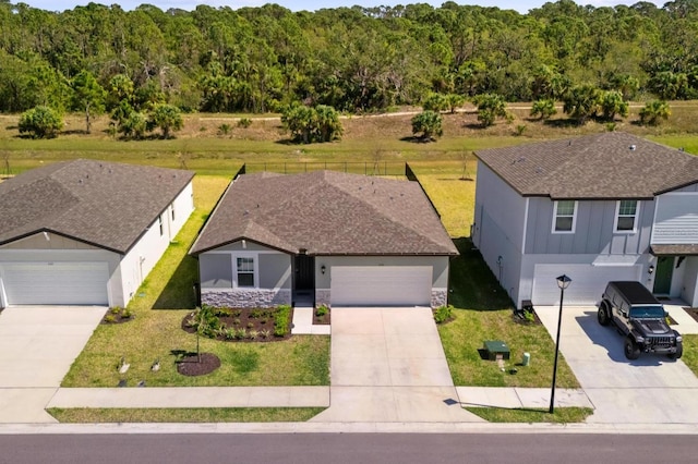 view of front of property featuring board and batten siding, a forest view, driveway, and a front yard