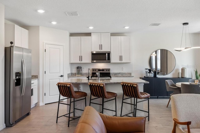 kitchen featuring light wood finished floors, open floor plan, white cabinets, and appliances with stainless steel finishes