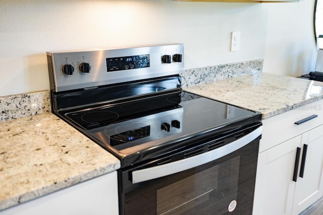 kitchen featuring light stone counters, white cabinets, and stainless steel range with electric cooktop