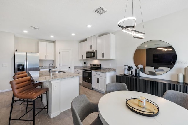 kitchen with visible vents, light wood finished floors, a breakfast bar, a sink, and stainless steel appliances