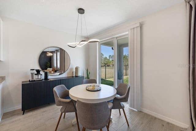 dining area with light wood-type flooring and baseboards