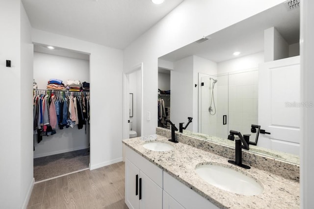 full bath with visible vents, wood finished floors, a stall shower, and a sink