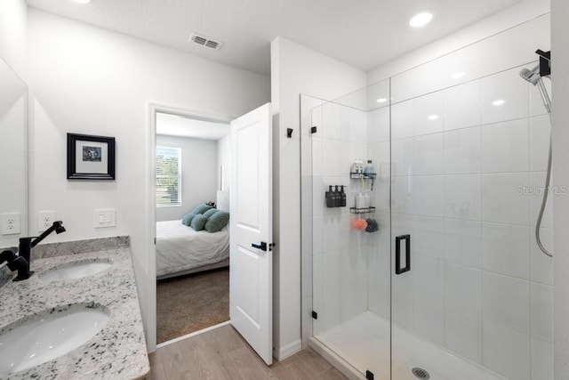 ensuite bathroom featuring a sink, visible vents, a stall shower, and wood finished floors