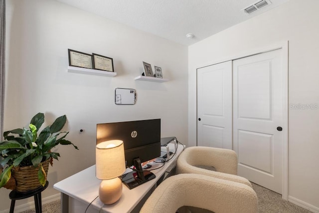 carpeted office with visible vents, a textured ceiling, and baseboards