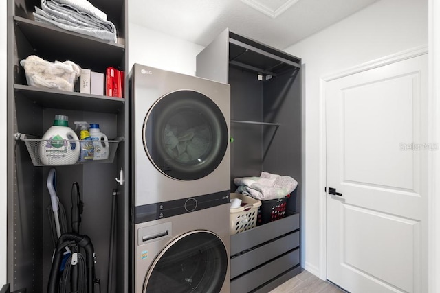 laundry area featuring laundry area, stacked washer and dryer, and light wood-style floors