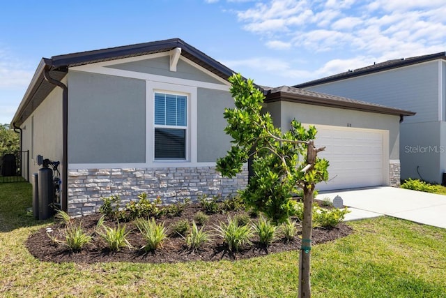 view of front facade with stucco siding, driveway, stone siding, an attached garage, and a front yard