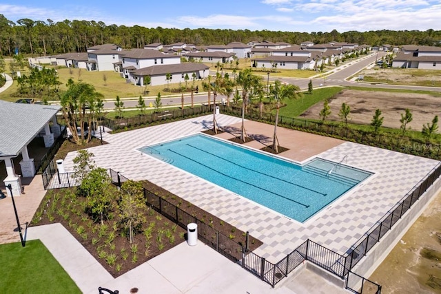 view of swimming pool with a residential view, a patio, and fence