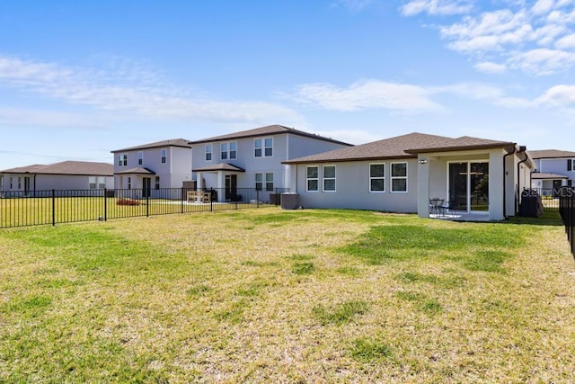 rear view of house featuring a yard, a residential view, a fenced backyard, and stucco siding