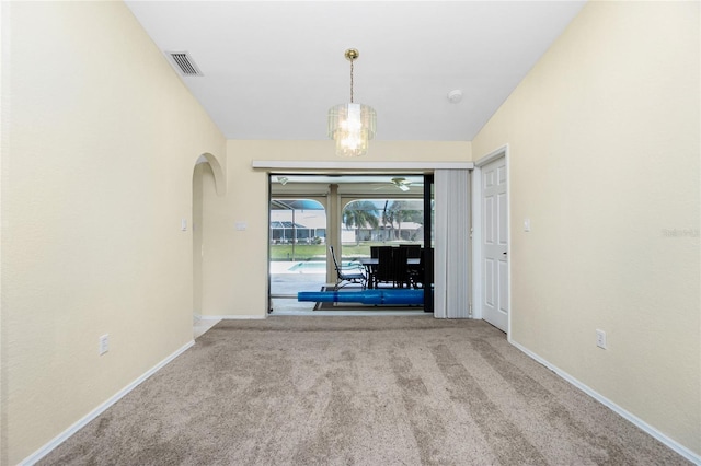 interior space with visible vents, carpet floors, arched walkways, an inviting chandelier, and baseboards