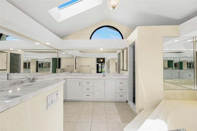 bathroom featuring plenty of natural light, vaulted ceiling with skylight, tile patterned flooring, a bath, and vanity