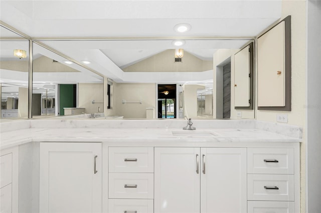 full bath featuring lofted ceiling, double vanity, and a sink