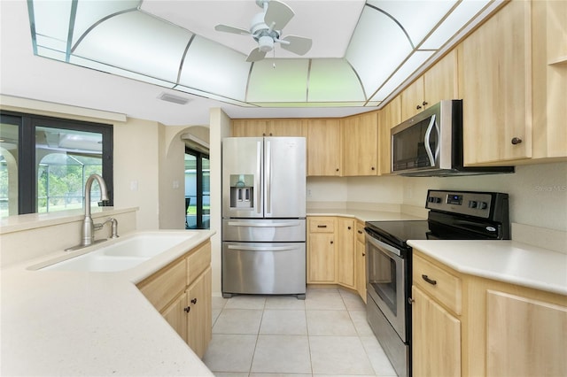 kitchen with light brown cabinetry, a sink, stainless steel appliances, light countertops, and light tile patterned floors