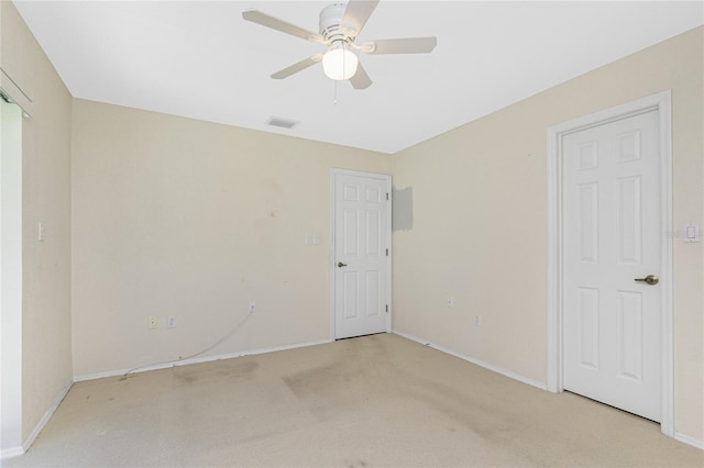 unfurnished room with visible vents, light colored carpet, baseboards, and a ceiling fan