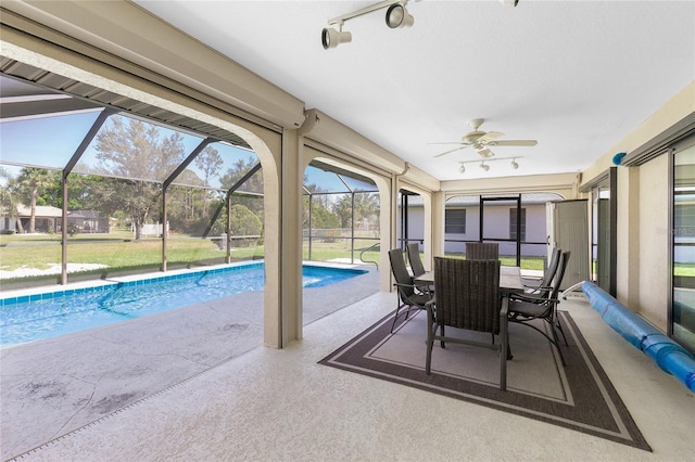 unfurnished sunroom featuring track lighting and a ceiling fan