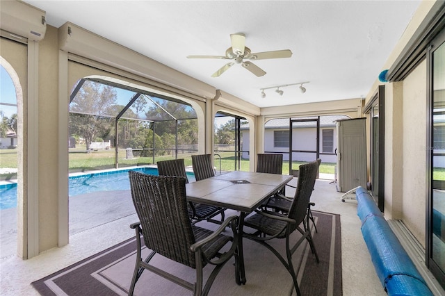 sunroom featuring rail lighting, a wall mounted air conditioner, and ceiling fan