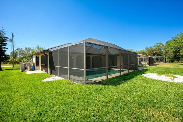 rear view of house with an outdoor pool, glass enclosure, and a lawn