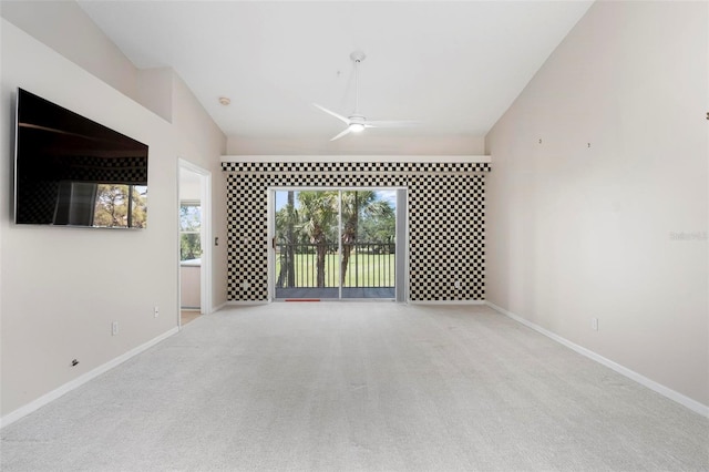 spare room featuring baseboards, lofted ceiling, a ceiling fan, and carpet