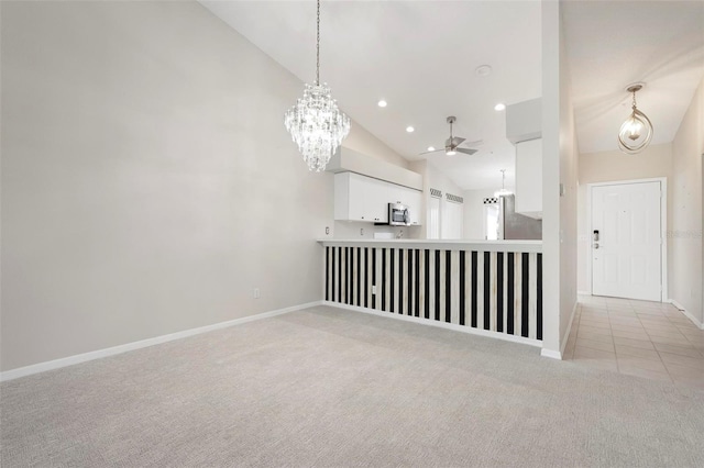 kitchen with appliances with stainless steel finishes, light carpet, white cabinetry, decorative light fixtures, and ceiling fan with notable chandelier