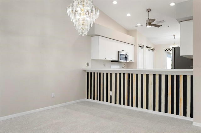 kitchen with baseboards, white cabinets, stainless steel microwave, carpet flooring, and ceiling fan with notable chandelier