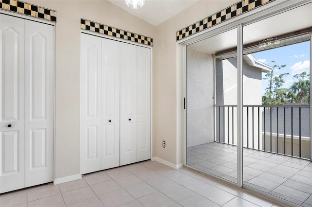 unfurnished bedroom featuring tile patterned flooring, vaulted ceiling, and baseboards