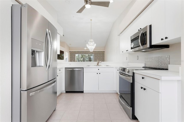 kitchen with light tile patterned floors, a sink, light countertops, appliances with stainless steel finishes, and ceiling fan with notable chandelier