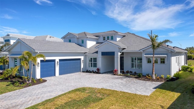 view of front of home with a front lawn, a tile roof, stucco siding, decorative driveway, and an attached garage