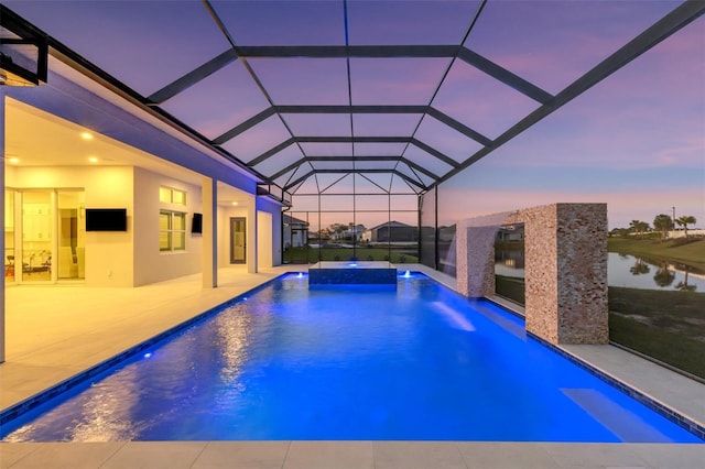 pool featuring glass enclosure, a patio area, and a water view