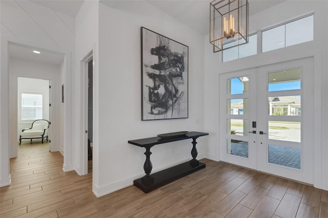 entrance foyer with a notable chandelier, french doors, baseboards, and wood tiled floor