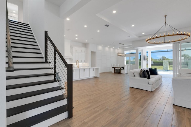 living area with light wood-type flooring, visible vents, recessed lighting, stairway, and a chandelier