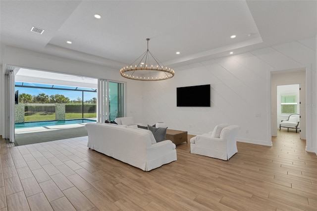 living area with visible vents, a chandelier, recessed lighting, light wood-style floors, and a raised ceiling