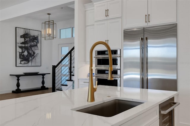 kitchen featuring light stone counters, stainless steel appliances, white cabinets, and hanging light fixtures